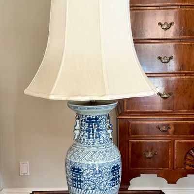 Sale Photo Thumbnail #133: Pair of large Chinese blue and white double “Happiness” porcelain style vase lamps from Chinese artisans in towns such as Jingdezhen, China. The lamp decoration, includes traditional motifs and floral scrollwork, dark carved base, brass toned hardware