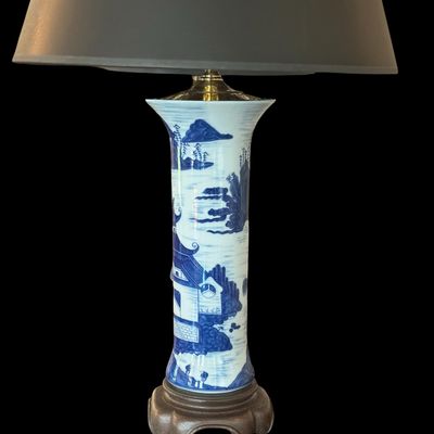 Sale Photo Thumbnail #137: A sophisticated pair of table lamps featuring cylindrical porcelain bodies decorated in classic blue and white landscape pattern, depicting pagodas and mountainous scenery. The porcelain bases are mounted on carved wooden stands and topped with modern bra