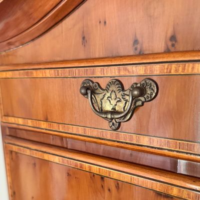Sale Photo Thumbnail #104: This exquisite Queen Anne style highboy features a classic bonnet-top (or swan's neck) pediment adorned with a central carved shell motif and finials. The piece is constructed with rich, figured walnut veneers, showcasing intricate grain patterns across t