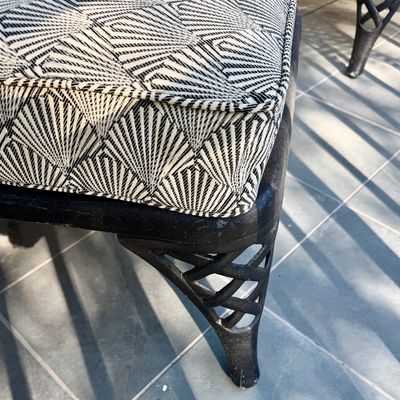 Sale Photo Thumbnail #280: This  pair of vintage chaise lounges features a durable cast aluminum frame finished in a matte black powder coat, characterized by intricate, lattice-style openwork on the frame and legs. This piece is mounted on two functional wheels, facilitating easy 