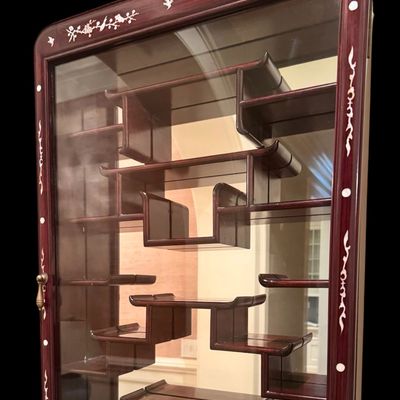 Sale Photo Thumbnail #192: Exquisite wall-mounted curio cabinet, often referred to as a “bogu” shelf constructed from dense rosewood and features intricate beautiful mother-of-pearl inlay. The frame is adorned with delicate floral and avian motifs and enclosed by a glass-fronte
