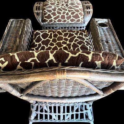 Sale Photo Thumbnail #291: Constructed from woven wicker and rattan, featuring a distinctive, wide-arm design with an integrated circular cup holder on the right armrest. The chair is upholstered in bold, animal-print fabric featuring a giraffe-inspired pattern. Its structural comp