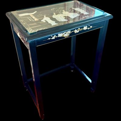 Sale Photo Thumbnail #174: Vintage Chinese nesting tables featuring a deep black lacquer finish with intricate applied porcelain figurines. Each table top is protected with a glass insert depicting East Asian scenes. The tables are constructed with clean, minimalist lines typical o
