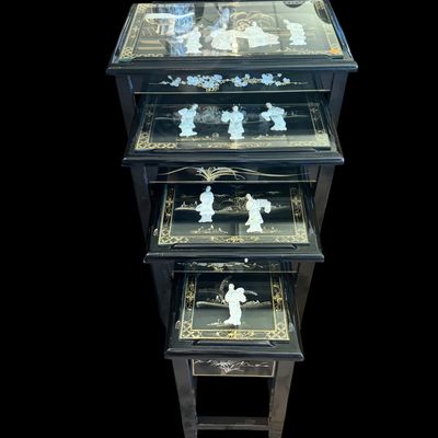 Sale Photo Thumbnail #169: Vintage Chinese nesting tables featuring a deep black lacquer finish with intricate applied porcelain figurines. Each table top is protected with a glass insert depicting East Asian scenes. The tables are constructed with clean, minimalist lines typical o