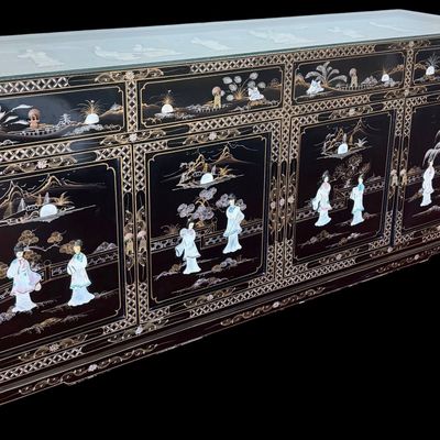 Sale Photo Thumbnail #175: A large black lacquer and mother-of-pearl inlaid figural sideboard depicting the popular “Royal Ladies” narrative scene. Constructed with four central cabinet doors and four upper drawers. The craftsmanship reflects the traditional East Asian furnitur