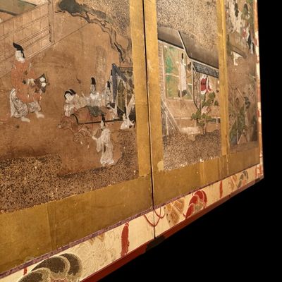 Sale Photo Thumbnail #5: Impressive Japanese eight-panel folding screen featuring hand painted narrative scenes of figures in traditional dress, architecture, and landscapes in muted earth tones with colorful accents. The paintings are framed by gold tone borders, decorative silk