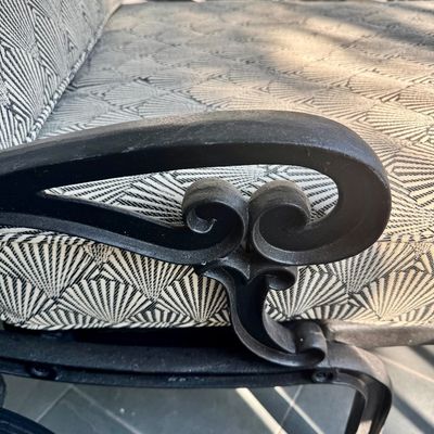 Sale Photo Thumbnail #279: This  pair of vintage chaise lounges features a durable cast aluminum frame finished in a matte black powder coat, characterized by intricate, lattice-style openwork on the frame and legs. This piece is mounted on two functional wheels, facilitating easy 