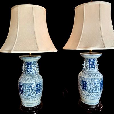 Sale Photo Thumbnail #132: Pair of large Chinese blue and white double “Happiness” porcelain style vase lamps from Chinese artisans in towns such as Jingdezhen, China. The lamp decoration, includes traditional motifs and floral scrollwork, dark carved base, brass toned hardware