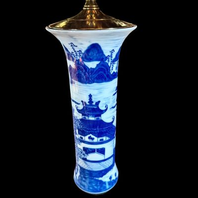 Sale Photo Thumbnail #138: A sophisticated pair of table lamps featuring cylindrical porcelain bodies decorated in classic blue and white landscape pattern, depicting pagodas and mountainous scenery. The porcelain bases are mounted on carved wooden stands and topped with modern bra