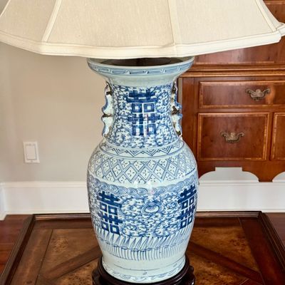 Sale Photo Thumbnail #134: Pair of large Chinese blue and white double “Happiness” porcelain style vase lamps from Chinese artisans in towns such as Jingdezhen, China. The lamp decoration, includes traditional motifs and floral scrollwork, dark carved base, brass toned hardware