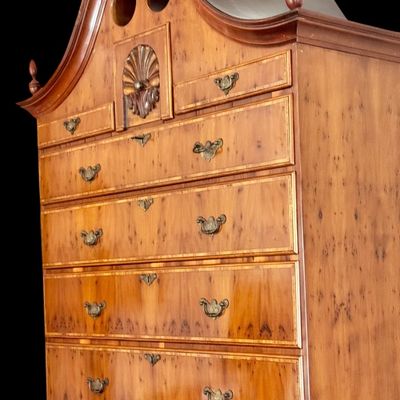 Sale Photo Thumbnail #101: This exquisite Queen Anne style highboy features a classic bonnet-top (or swan's neck) pediment adorned with a central carved shell motif and finials. The piece is constructed with rich, figured walnut veneers, showcasing intricate grain patterns across t