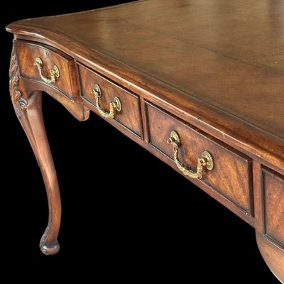 Sale Photo Thumbnail #67: This is a stunning Theodore Alexander partners style writing desk constructed with solid mahogany wood with a beautiful leather tooled top. A rich warm finish showcases the natural grain pattern. The front features a series of 4 drawers equipped with orna