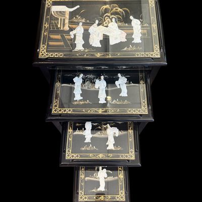 Sale Photo Thumbnail #168: Vintage Chinese nesting tables featuring a deep black lacquer finish with intricate applied porcelain figurines. Each table top is protected with a glass insert depicting East Asian scenes. The tables are constructed with clean, minimalist lines typical o