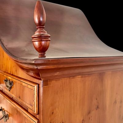 Sale Photo Thumbnail #109: This exquisite Queen Anne style highboy features a classic bonnet-top (or swan's neck) pediment adorned with a central carved shell motif and finials. The piece is constructed with rich, figured walnut veneers, showcasing intricate grain patterns across t