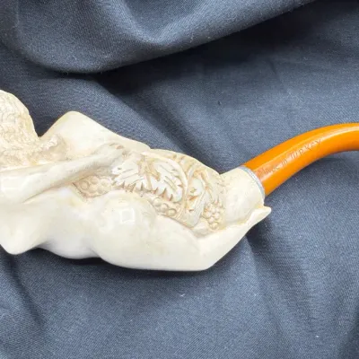 Sale Photo Thumbnail #12: Hand-carved meerschaum tobacco pipe depicting a reclining female figure with grape leaves, featuring an amber-colored stem marked "MADE IN TURKEY".