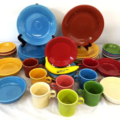 Sale Photo Thumbnail #23: Large collection of colorful Fiesta ceramic dinnerware, including plates, bowls, and mugs in various vibrant glazes.