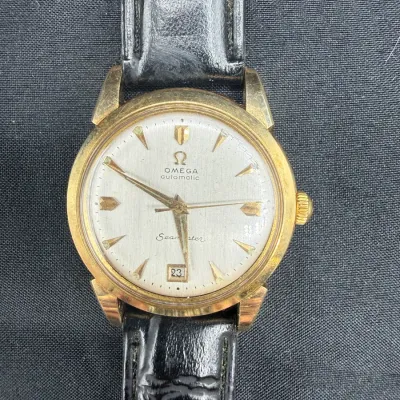 Sale Photo Thumbnail #25: Vintage Omega Seamaster Automatic wristwatch with a gold-plated or gold-filled case, silvered dial, date window at 6 o'clock, and black leather strap.