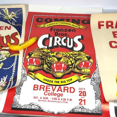 Sale Photo Thumbnail #4: Trio of vintage Franzen Bros. Circus posters featuring colorful graphics of big cats, acrobats, and a clown, displayed alongside a plastic banana for scale.