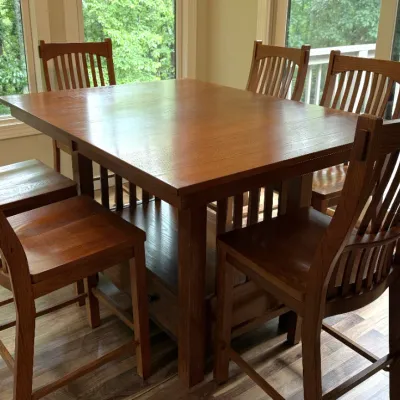 Sale Photo Thumbnail #18: Mission-style oak counter-height dining set featuring a square table with lower storage and six slat-back chairs in a warm amber finish.