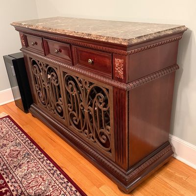 Sale Photo Thumbnail #11: Traditional dark wood sideboard cabinet featuring a faux marble top, scrollwork wrought iron door inserts, three upper drawers, and carved rope trim.