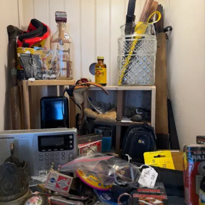 Sale Photo Thumbnail #68: An eclectic collection of vintage household and personal items, including a Grundig portable radio, matchboxes, small tools, and decorative collectibles displayed in a wooden cabinet.