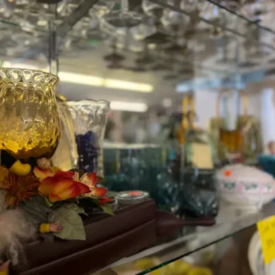 Sale Photo Thumbnail #55: Collection of vintage glass stemware, decorative amber glass candle holders, and small trinkets displayed on glass shelves.