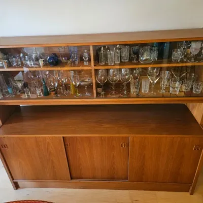 Danish Modern teak hutch credenza with glass sliding display doors on top and wooden sliding cabinet doors below, filled with various...