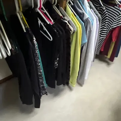 Selection of women's long-sleeve tops and t-shirts, including striped, solid, and patterned styles, hanging on plastic clothes hangers.