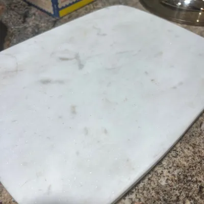 Rectangular white marble cutting board or pastry slab with subtle grey veining, resting on a speckled countertop.