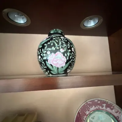 Chinese Famille Noire porcelain ginger jar decorated with hand-painted pink peonies and leafy green vines on a black ground, displayed on...