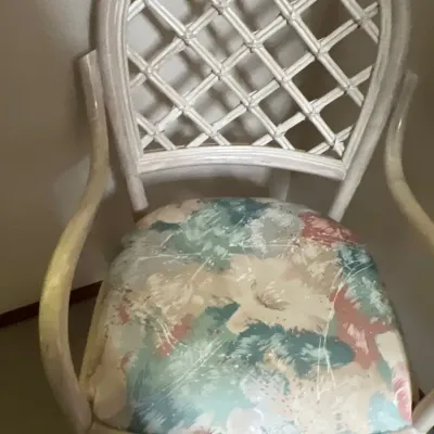 Vintage whitewashed rattan armchair featuring a trellis-style arched back and a floral upholstered seat cushion.
