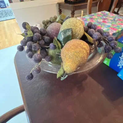 A clear glass pedestal centerpiece bowl filled with beaded, sugared decorative artificial fruit including pears, apples, and grapes.