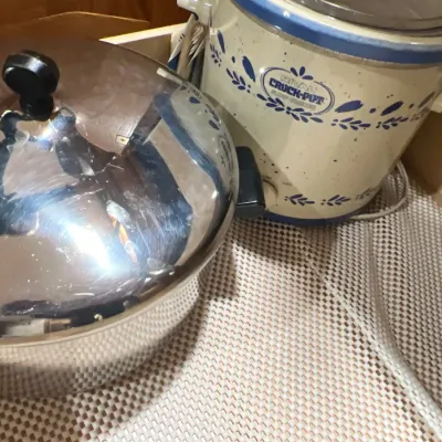 Stainless steel stockpot with lid alongside a vintage Rival Crock-Pot slow cooker featuring a blue floral motif.