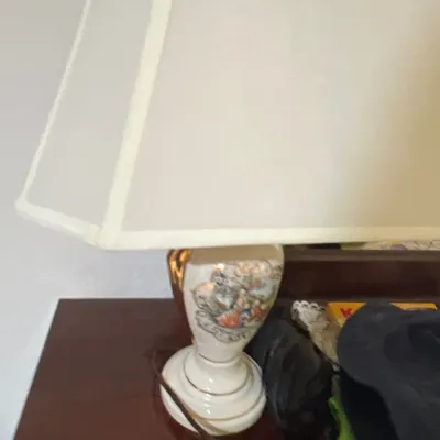 Vintage porcelain table lamp featuring a classic courtyard vignette with gold accents and a large cream fabric shade.