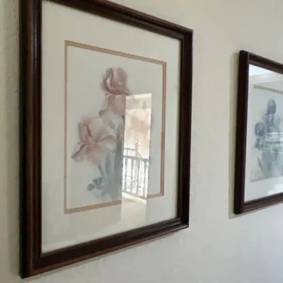 Framed floral watercolor prints in dark wood frames, featuring pastel iris blooms under glass.
