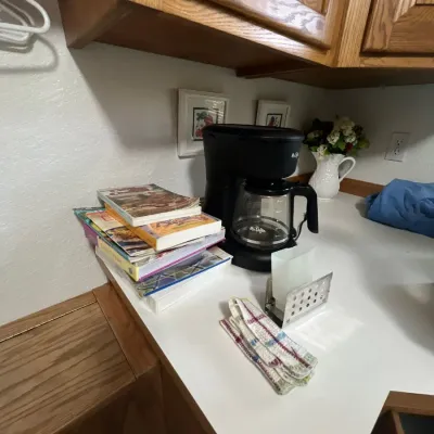 Black Mr. Coffee 12-cup drip coffee maker sitting on a kitchen counter alongside a stack of cookbooks and kitchen towels.