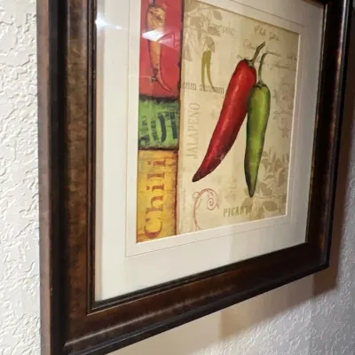 Framed culinary art print featuring red and green chili peppers in a dark wood frame with cream matting.