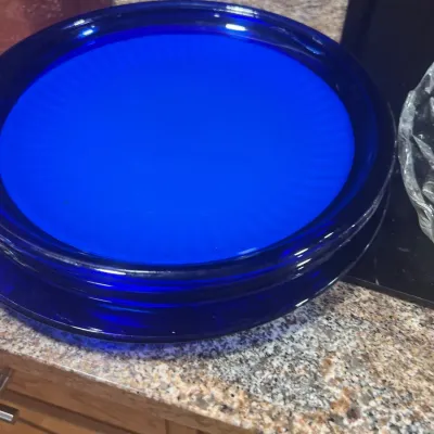 Stack of vintage cobalt blue glass dinner plates resting on a granite kitchen countertop.
