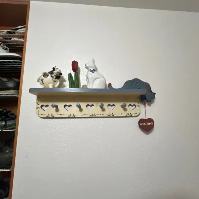 Country-style wooden wall coat rack with shelf, decorated with ceramic animal figurines and painted heart cutouts.