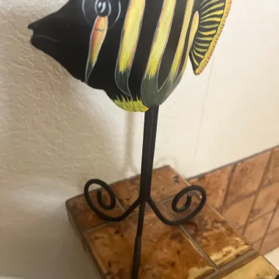 Hand-painted wooden fish sculpture mounted on a black wrought iron stand with scroll feet.