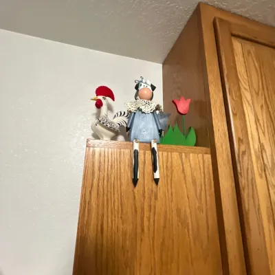 Collection of country-style decorative items, including a ceramic rooster figurine, a wooden shelf-sitter cow, and a wooden tulip cutout,...