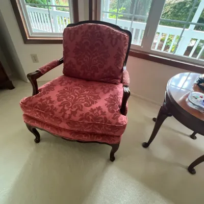 French Provincial style armchair upholstered in a dark pink damask fabric with a dark wood frame.