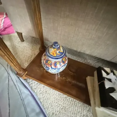 Hand-painted Talavera ceramic ginger jar sitting on the lower wooden shelf of an accent table.