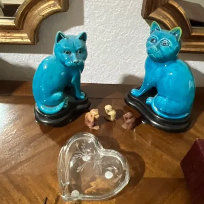Pair of vintage turquoise glazed ceramic cat figurines on wooden stands, accompanied by three miniature monkey figurines and an etched...
