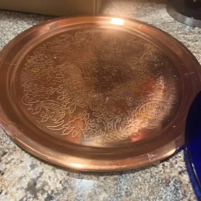 Round copper serving tray with intricate etched floral and scrollwork design