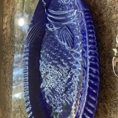 Cobalt blue glazed ceramic fish-shaped serving platter featuring detailed scale and fin textures.