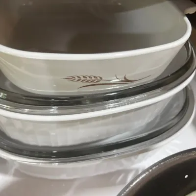 Stacked CorningWare casserole dishes featuring a wheat sheaf design, complete with clear glass lids.