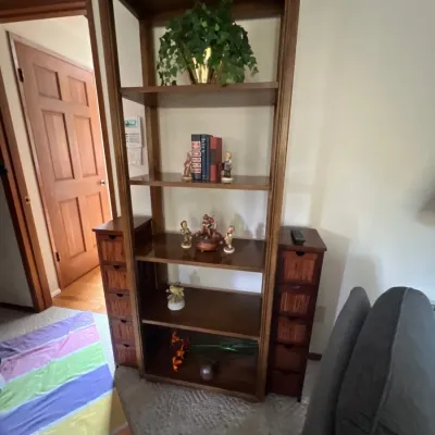 Tall vintage wooden shelving unit with open central display shelves flanked by side columns featuring small storage drawers.