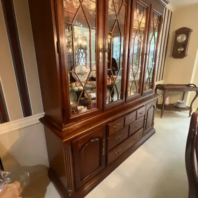 Traditional dark wood china hutch with glass-front cabinet doors, interior lighting, and lower storage drawers and side cabinets.