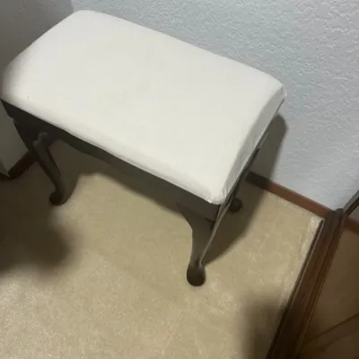 Traditional vanity stool or piano bench featuring a dark wood frame with cabriole legs and a cream-colored upholstered seat.